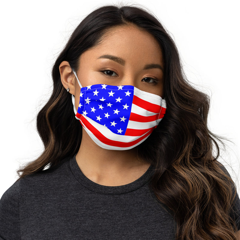A woman with brown hair wearing a premium white face mask with the United States of America flag imprinted red white and blue